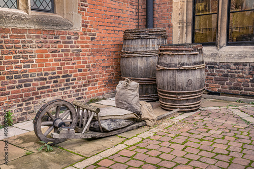 Decorative old barrels abandoned in a medieval street corner.
Very old rustic barrels along a wheelbarrow.