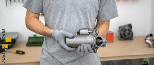 Mechanic inspects a car starter component while wearing gloves in a well-equipped garage, focusing on the details crucial for efficient repairs.