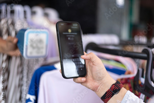 Indian customer woman hand holding smartphone doing online UPI payment in shopping mall clothing store market