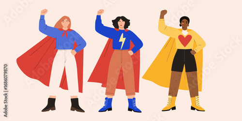 Three diverse women dressed as superheroes with their fists raised in a powerful stance
