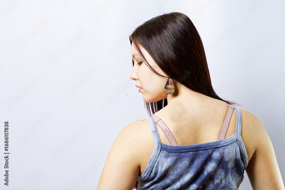 Fototapeta premium Lady in Blue Tie-Dye Top Posing Sideways With Tribal Earrings Rear View, copyspace