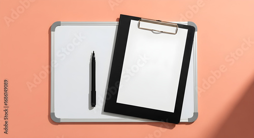 A black marker lies on a whiteboard next to a clipboard with blank paper