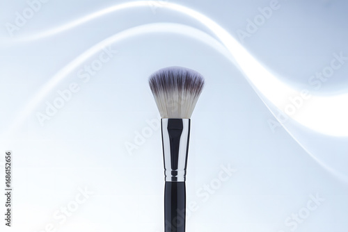 Close-up of a professional makeup brush with soft brown and pink bristles on a white background