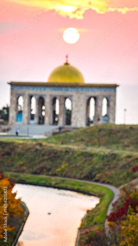 Obraz premium Blurry sunrise view of a temple, canal, and hillside