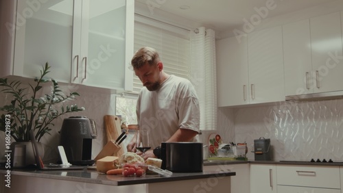 Caucasian man, 35 years old, focused on preparing food in serene kitchen. Cutting vegetables, using air fryer, enjoying calm daytime atmosphere.