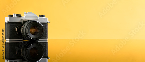 Capture memories with this vintage camera resting on reflective surface against bright yellow background