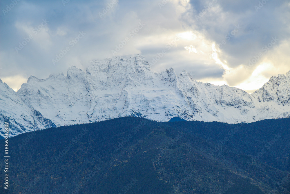 Obraz premium Jagged, snowy peaks loom under a cloudy sky Yala Snow Mountain, Sichuan, China