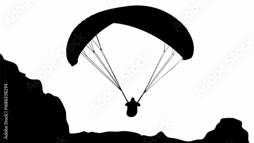 A silhouette of a paraglider soaring through the air with mountains in the background on a white sky view