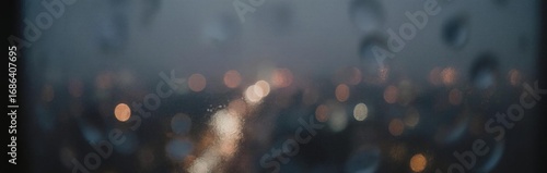 Moody and atmospheric view of city lights through a rain-streaked window.