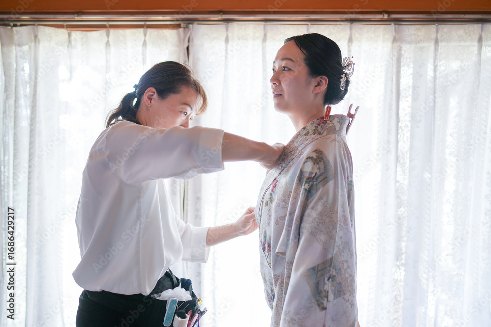 Obraz premium A woman is getting her clothes altered by another woman. The woman being altered is wearing a kimono