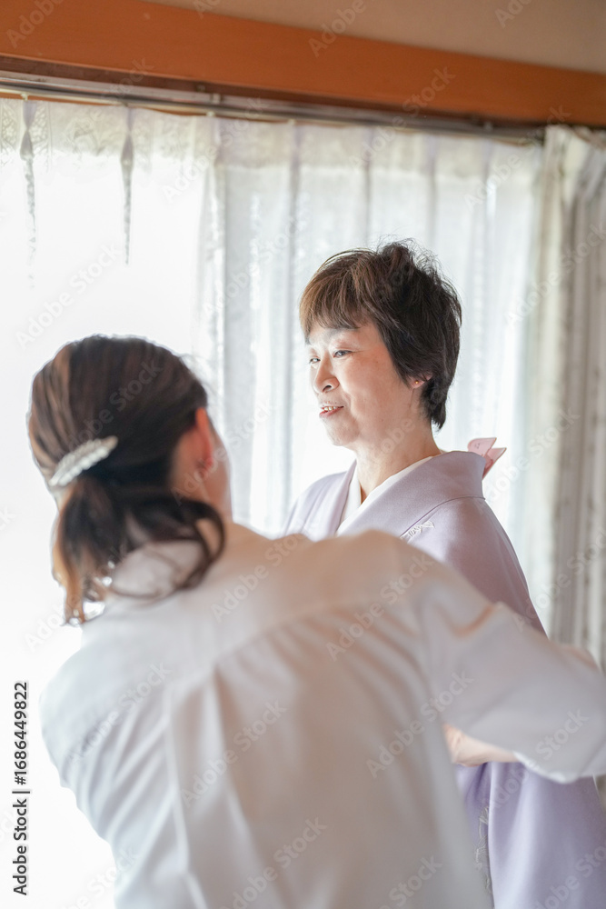 Obraz premium A woman in a white shirt is assisting another woman in a purple robe