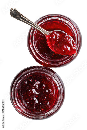 Two glass jars filled with red fruit preserves, topped with a silver spoon.  Overhead view
