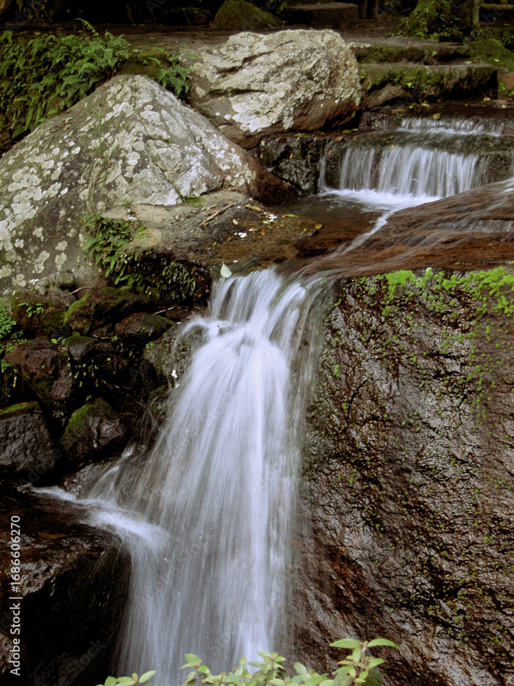 Fototapeta premium A closeup fast shutter photo of a mountain stream and waterfall in a park outside near the city of Taipei - the photo is taken right after sunset thus a bit dark