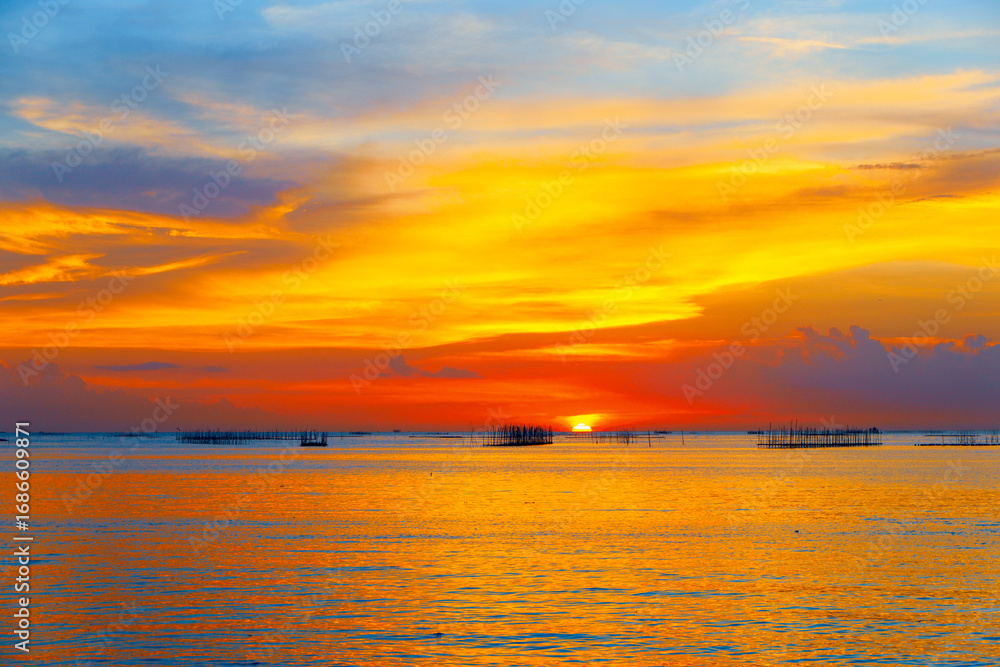 Fototapeta premium sunset in the sea. Beautiful colorful sky and cloud in twilight time background. Orange fluffy clouds and sun sunlight reflection in the blue sky.