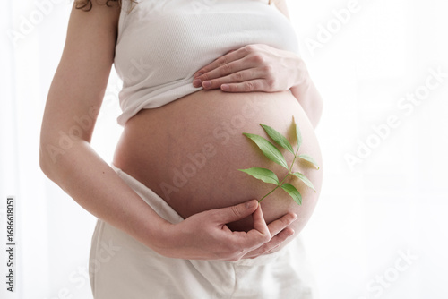 Pregnant woman holding leaves at belly