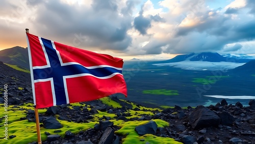 Norwegian flag waving on a hill with mountains and cloudy sky in the background on a summer day