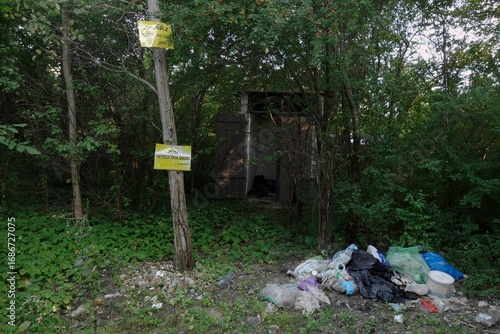 Garbage in forest with added information on trees - prohibition of throwing the litter about.