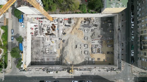 Aerial view construction site with a foundation pit of new skyscraper timelapse. Earthwork in excavation and backfilling of soil. Heavy machinery for earthmoving with crane, truck and bulldozer. 