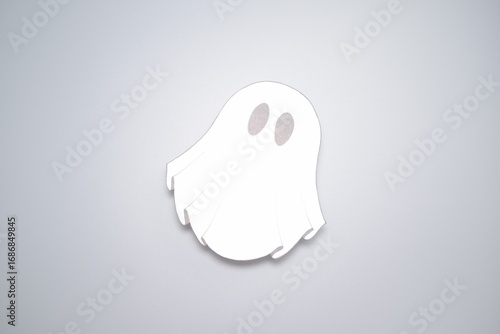White paper ghost on gray background. Blurred background. Halloween celebration. Halloween background