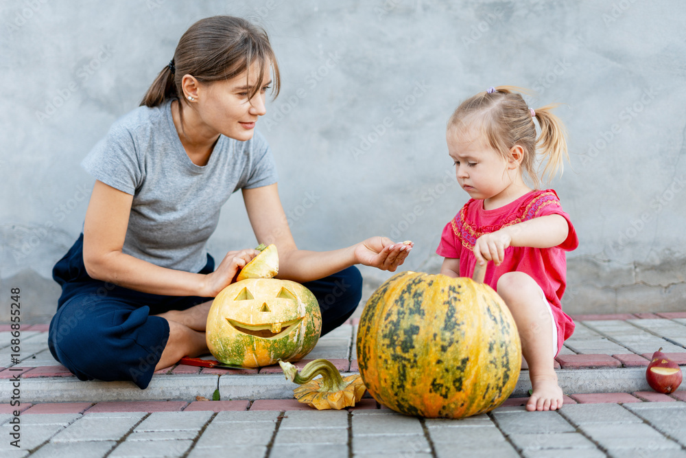Fototapeta premium Mother and daughter carving pumpkins for Halloween celebration