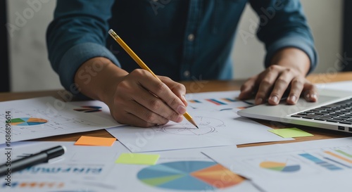 Person sketching diagrams with laptop and papers