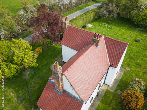 Aerial view of a new, red tiled roof seen on an old English farm house. Notice the multiple chimneys, for heating each room