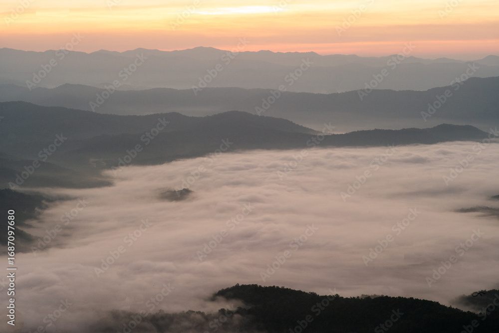 Fototapeta premium Mountain range covered by the white fog with sunrise sky in the morning
