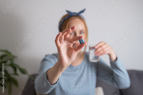 Middle age woman holding blue pills with fingers .Health care, dietary supplements, treatment of depression and diseases