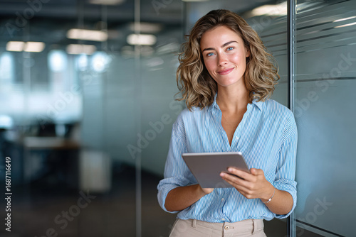 Confident businesswoman using tablet in modern office, female professional with digital technology at workplace - young business woman with tablet computer