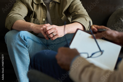 Fototapete Caucasian young adult man sitting with hands clasped during counseling session,