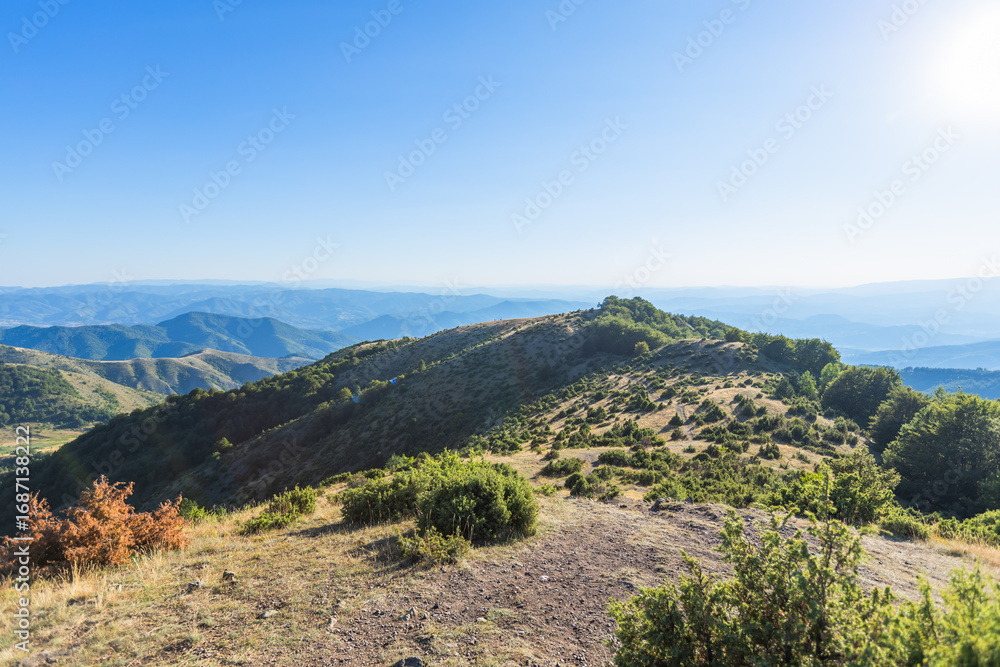 Fototapeta premium Stunning mountain ridge landscape with layered hills extending to horizon under clear blue sky