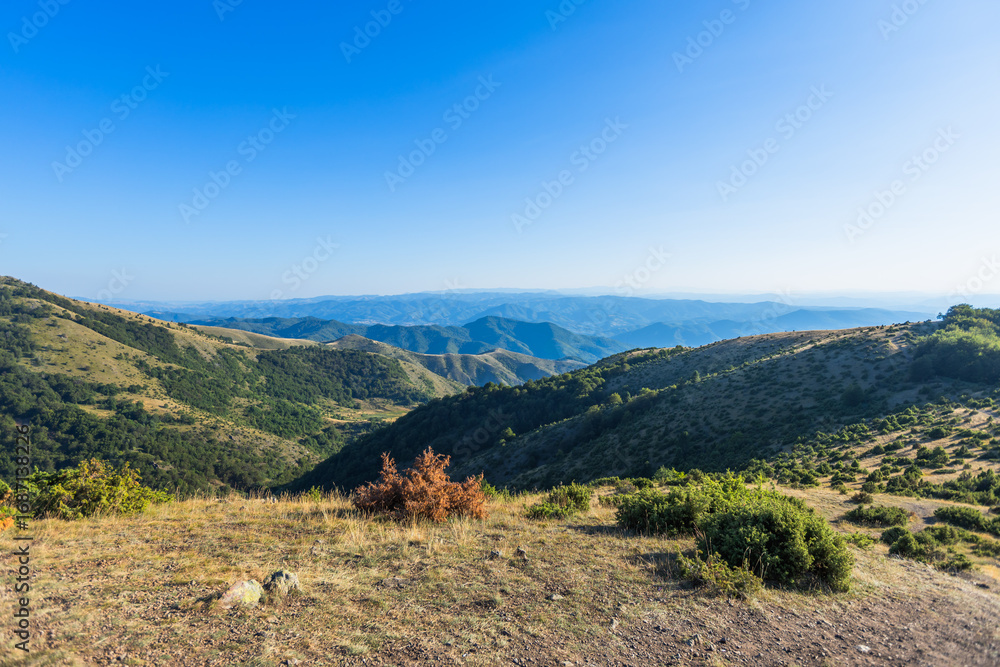 Fototapeta premium Stunning mountain ridge landscape with layered hills extending to horizon under clear blue sky