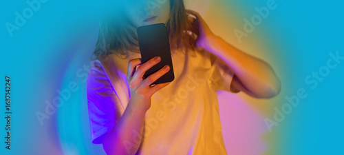 Woman texting SMS message on mobile phone. Woman holding smartphone and reading message on a neon glowing background