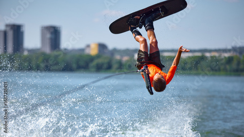 Photos Boy wakeboarder upside down flip stunt on river in bright orange shirt