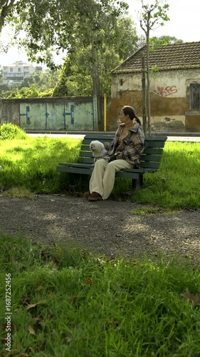 A girl sits with a dog on a bench on a sunny day