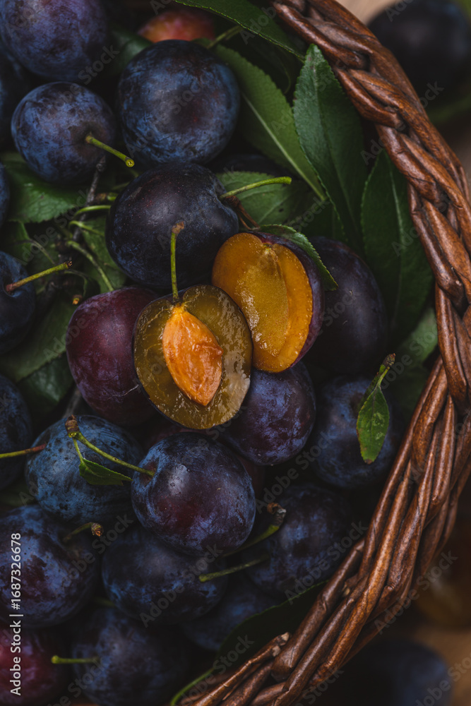 Fototapeta premium a plum cut in half lies on top of other whole plums