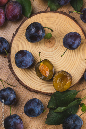 a plum cut in half lies on a piece of wood