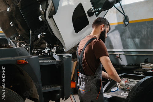 Auto mechanic repairing truck air conditioning system in garage