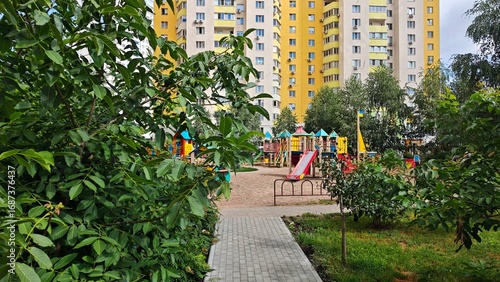Colorful playground surrounded by greenery with high-rise apartment buildings in the background