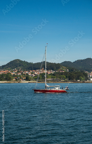 A sailboat in the estuaries of Galicia sails through the estuary to reach the sea.