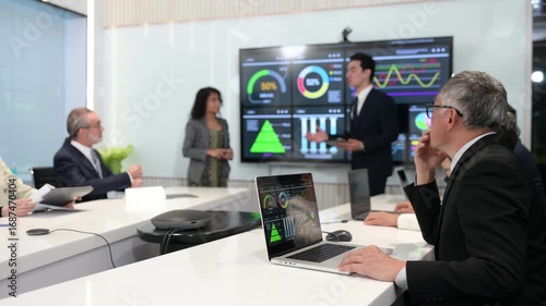 Business team in modern meeting room discussing data analytics on digital screen with charts and graphs, representing teamwork, strategy, innovation, and corporate success.