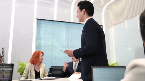 Business team in modern meeting room discussing data analytics on digital screen with charts and graphs, representing teamwork, strategy, innovation, and corporate success.