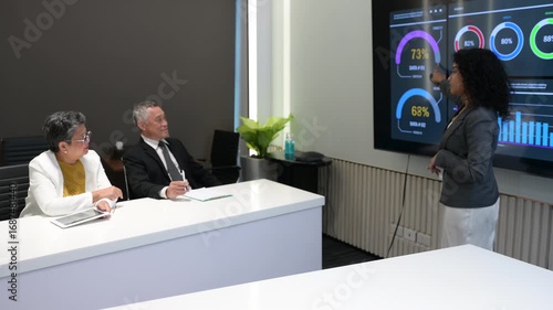 Business team in modern meeting room discussing data analytics on digital screen with charts and graphs, representing teamwork, strategy, innovation, and corporate success.