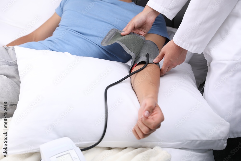 Fototapeta premium Doctor checking man's heart rate and blood pressure via sphygmomanometer at home, closeup