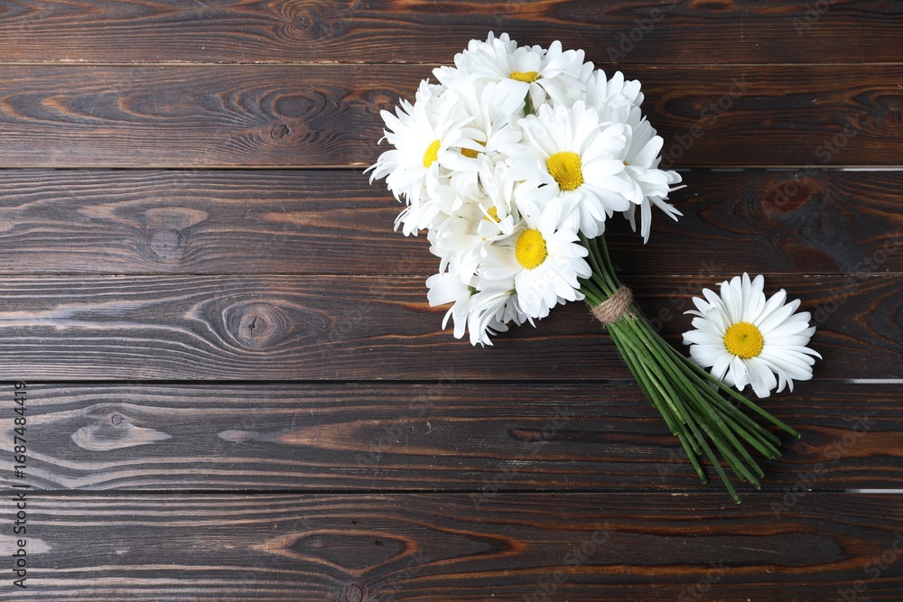 Obraz premium Bouquet of beautiful chamomile flowers on wooden table, top view. space for text