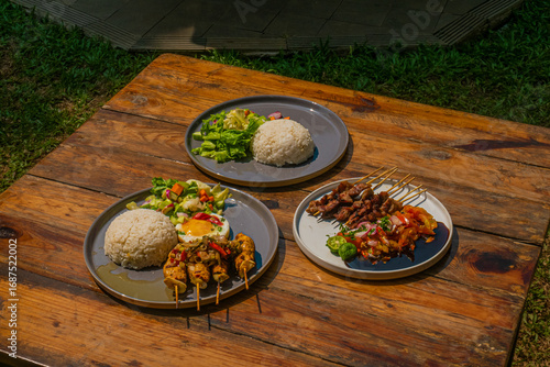 Delicious grilled skewers, rice, and fresh salad on a rustic wooden table, ready to eat now