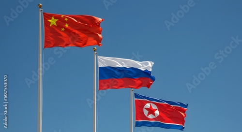 Three National Flags of China Russia and North Korea Against a Clear Blue Sky