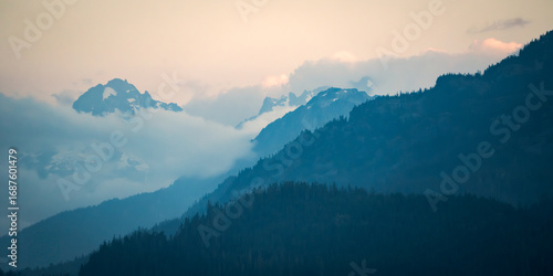 Fototapeta Naklejka Na Ścianę i Meble -  Looking across the layers of forest and mountains in the clouds at sunset near Whistler, Canada