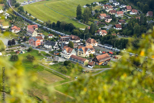 Fototapeta Naklejka Na Ścianę i Meble -  A picturesque view of a small German village with cozy houses, green fields, and hills. The rural landscape conveys the atmosphere of tranquility and harmony in Germany.