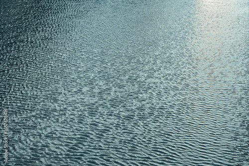 Ripples over a water surface in cool afternoon.
Tranquil textured aquatic scene of a river.